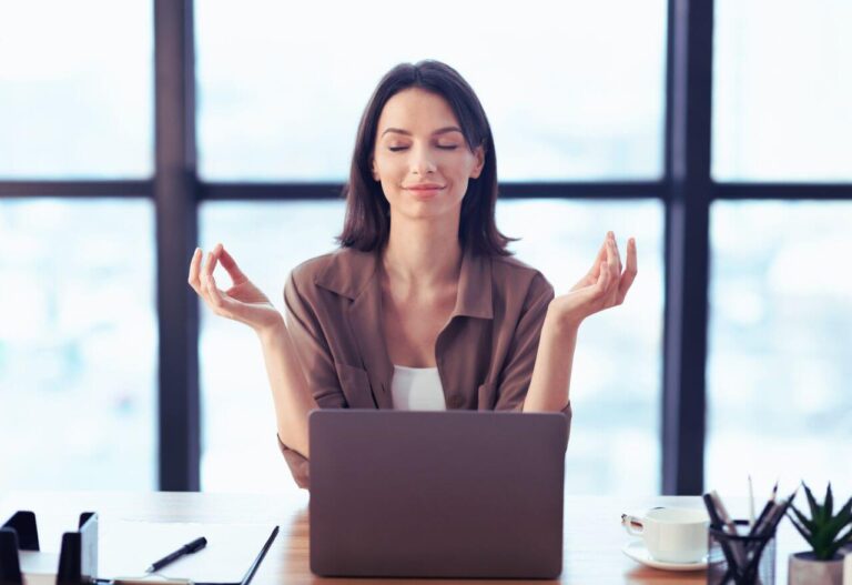 woman meditating at her desk looking calm