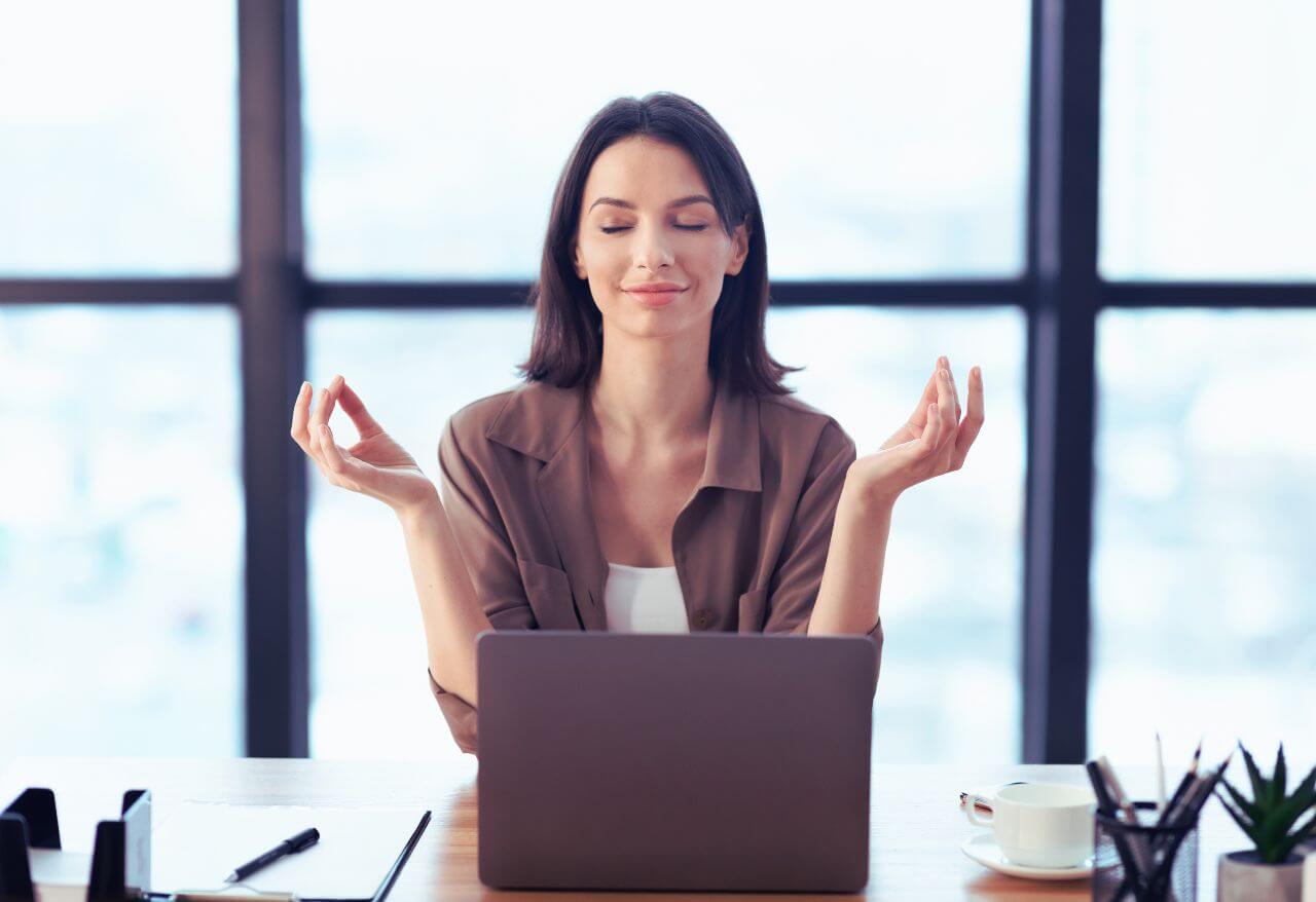 woman meditating at her desk looking calm